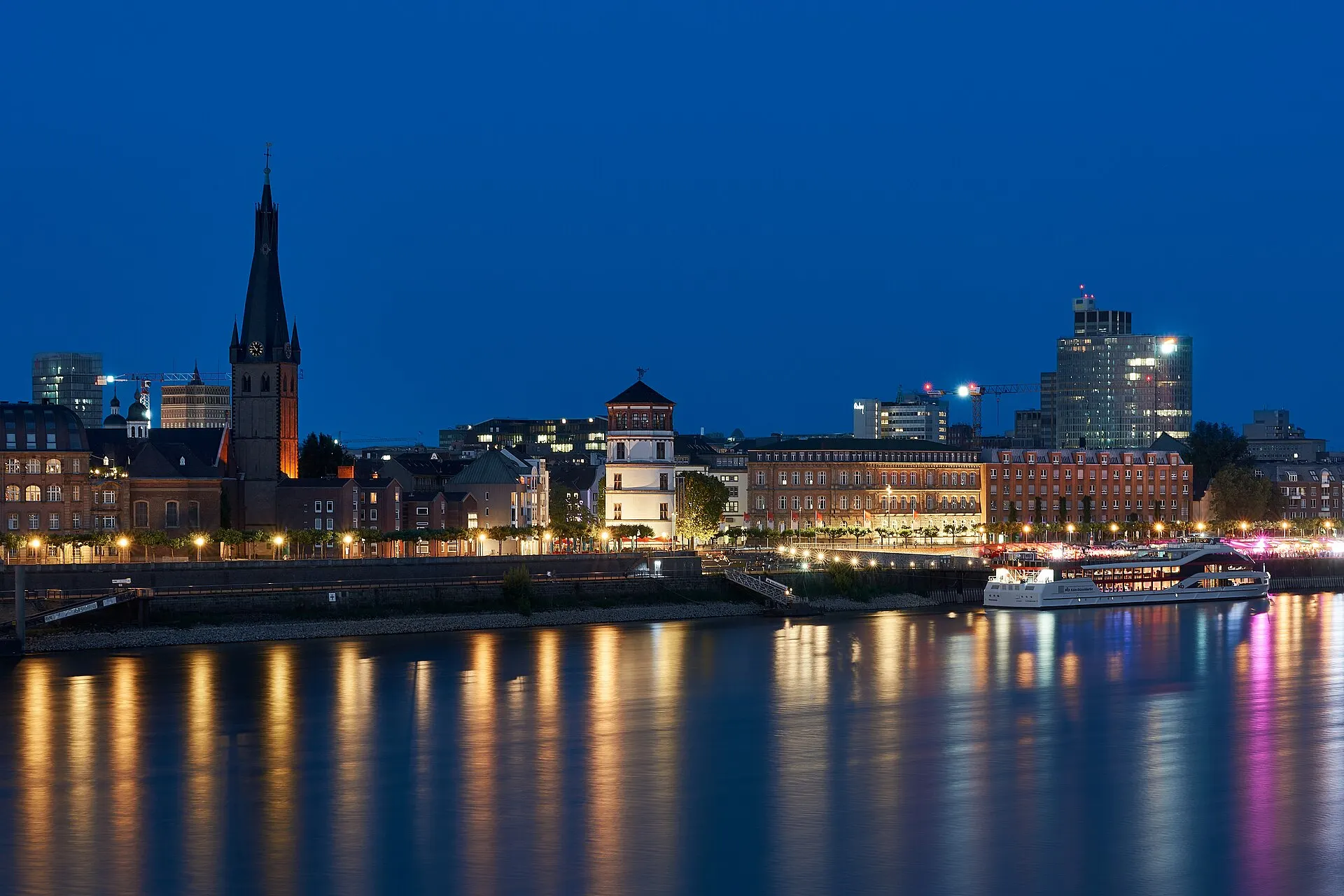 Belebte Rheinuferpromenade in Düsseldorf mit Blick auf den Rhein